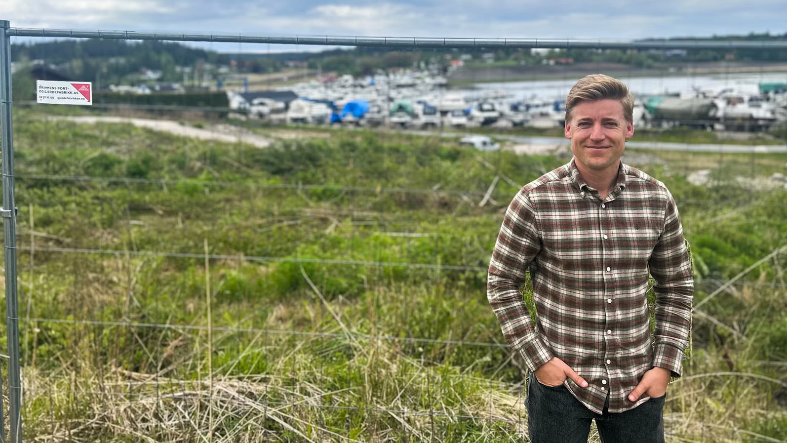 Kundeansvarlig Didrik Fosby på tomten til Høysand Brygge, med båthavnen i bakgrunnen